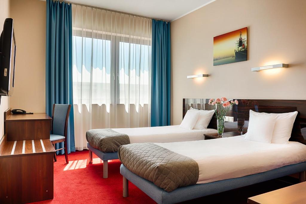 a hotel room with two beds and a window at Focus Hotel Gdańsk in Gdańsk