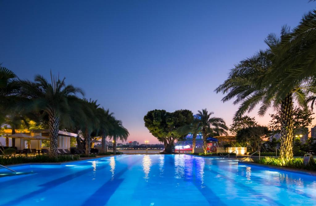 a large swimming pool with palm trees at night at White Swan Hotel in Guangzhou
