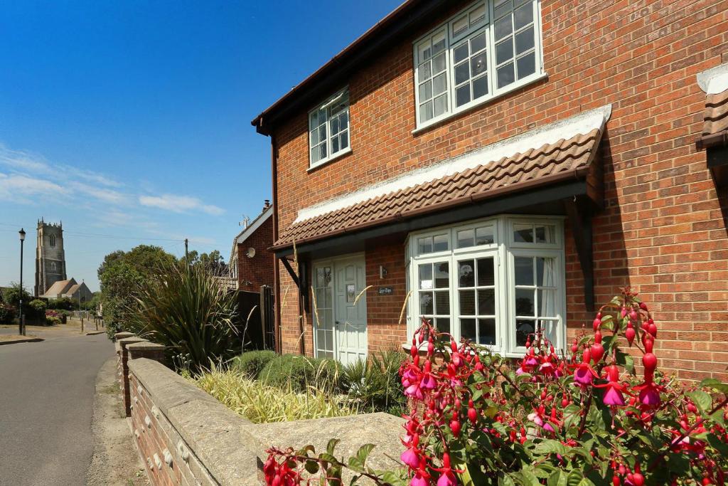 ein Backsteinhaus mit rosa Blumen davor in der Unterkunft Lazy Days Cottage in Winterton-on-Sea