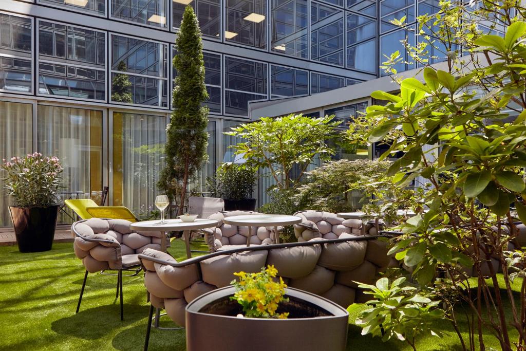- un jardin avec une table et des chaises dans un bâtiment dans l'établissement Mercure Paris la Défense Grande Arche, à Nanterre