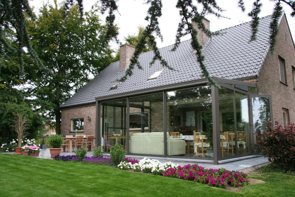 een huis met glazen deuren en bloemen in de tuin bij B&B Artiriacumhoeve in Zedelgem