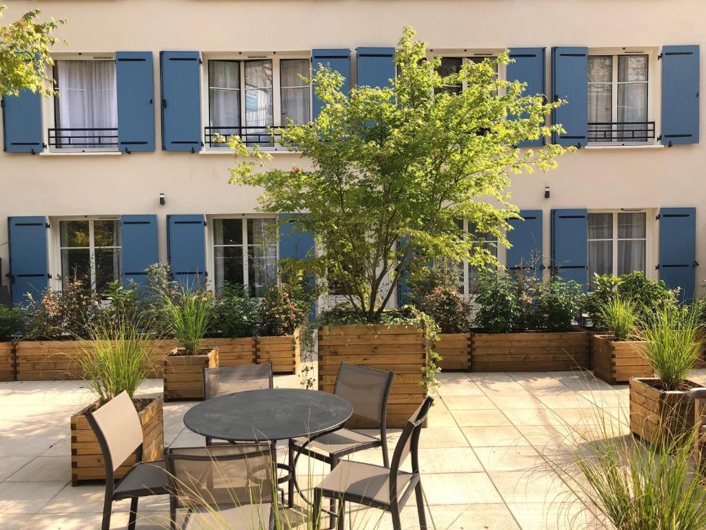 a patio with a table and chairs in front of a building at Les Maisons d'Eugène Appart'Hôtel - Centre Historique in Honfleur