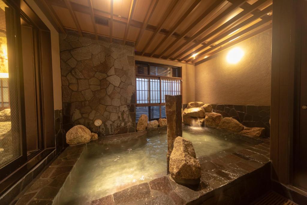 a hot tub in a room with rocks in it at Dormy Inn Premium Namba ANNEX Natural Hot Spring in Osaka