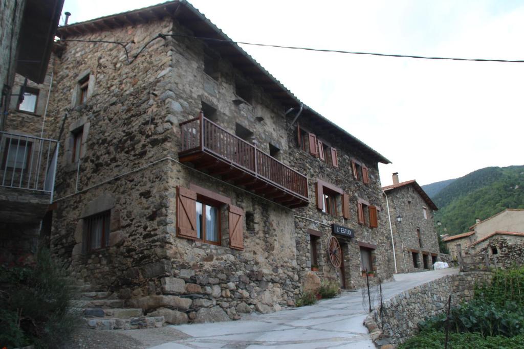 un antiguo edificio de piedra con balcón en una calle en Apartaments Can Bundanci en Setcases