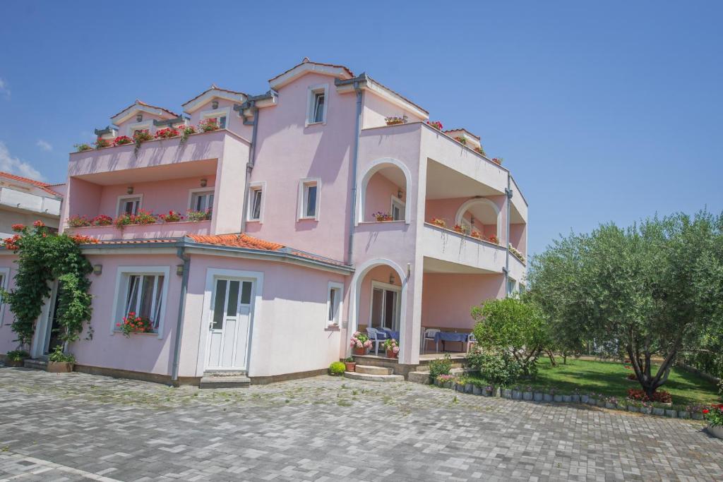 een roze huis met een balkon op een kinderkopje bij Bed and Breakfast Helena in Kaštela