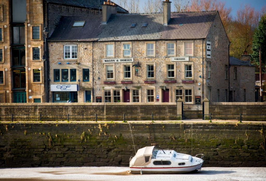 un petit bateau dans l'eau devant les bâtiments dans l'établissement Wagon & Horses, à Lancaster