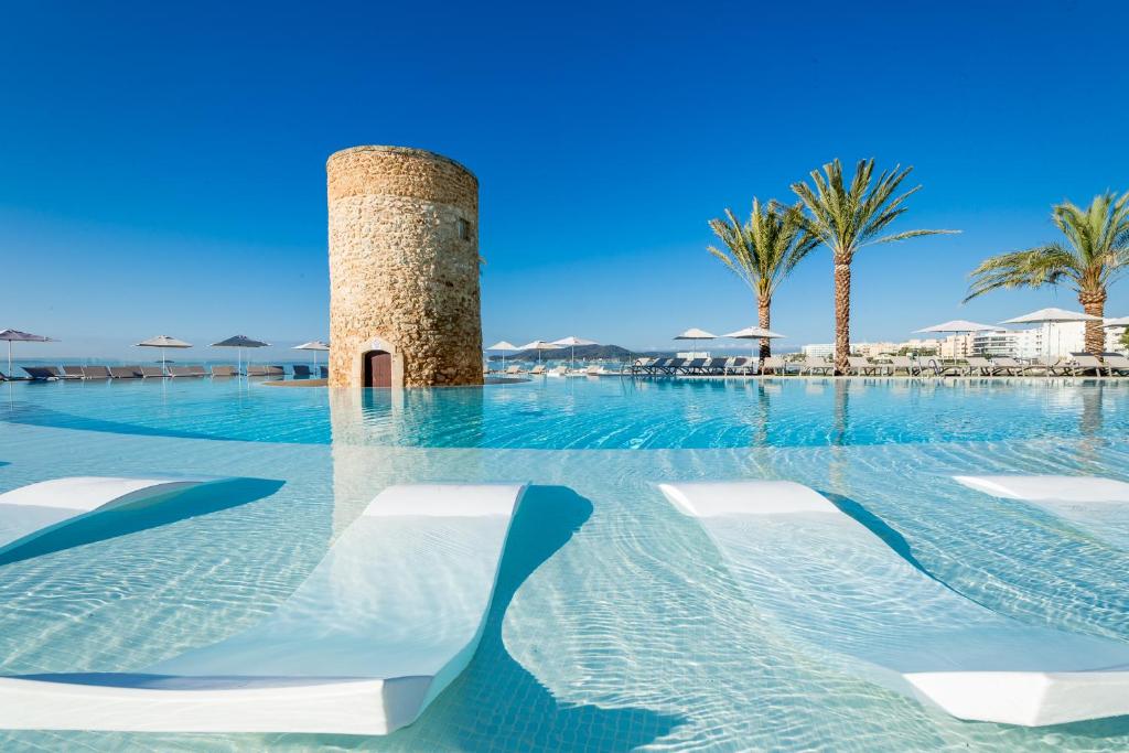 una piscina con sedie e una torre in acqua di Hotel Torre del Mar - Ibiza a Playa d'en Bossa