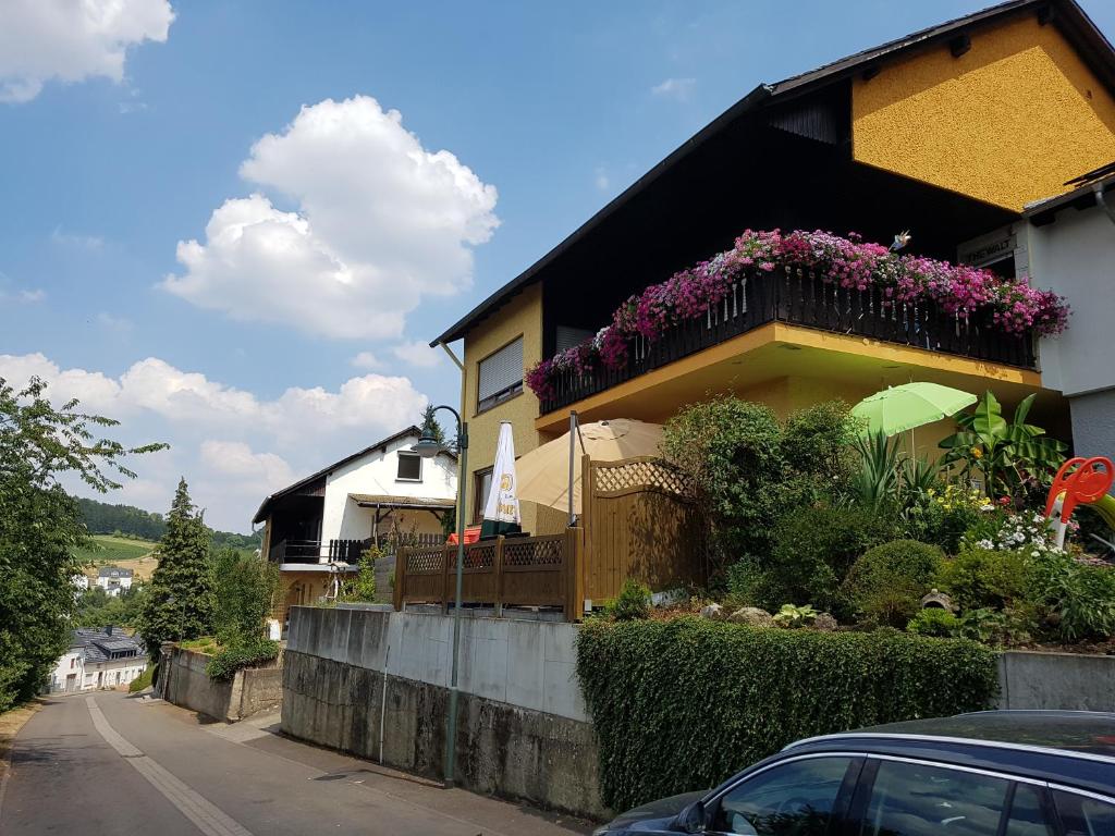 uma casa com uma varanda com flores em Ferienwohnung Hub em Nittel