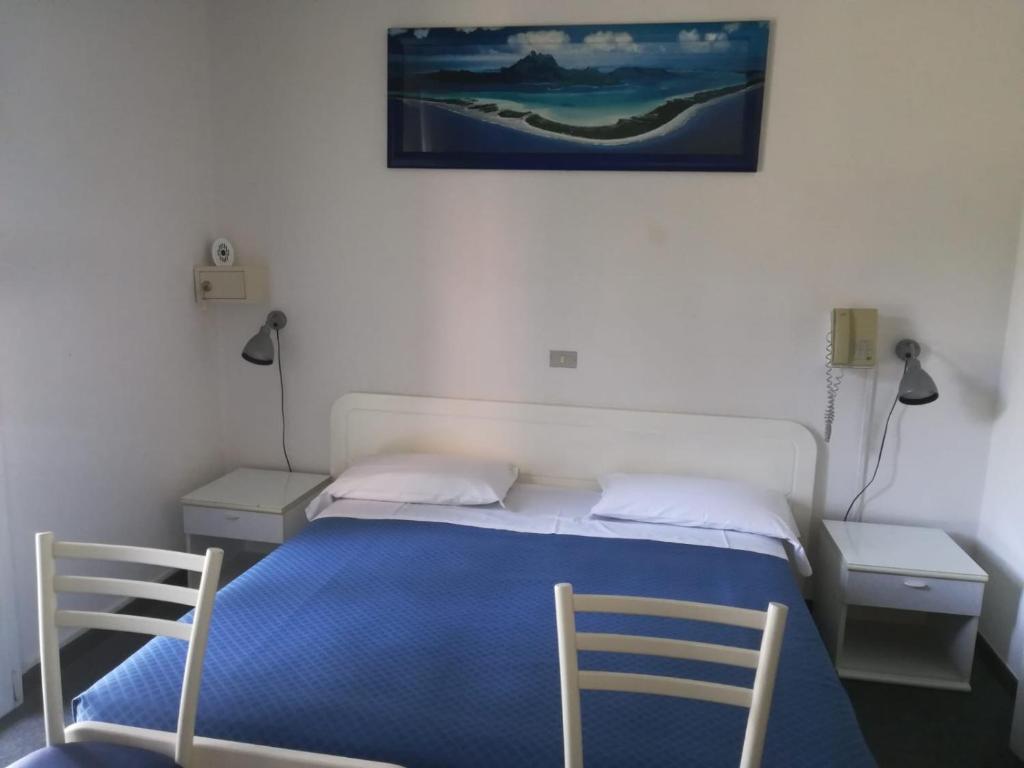 um quarto com uma cama azul e 2 cadeiras em Hotel Tuscolano em Bolonha