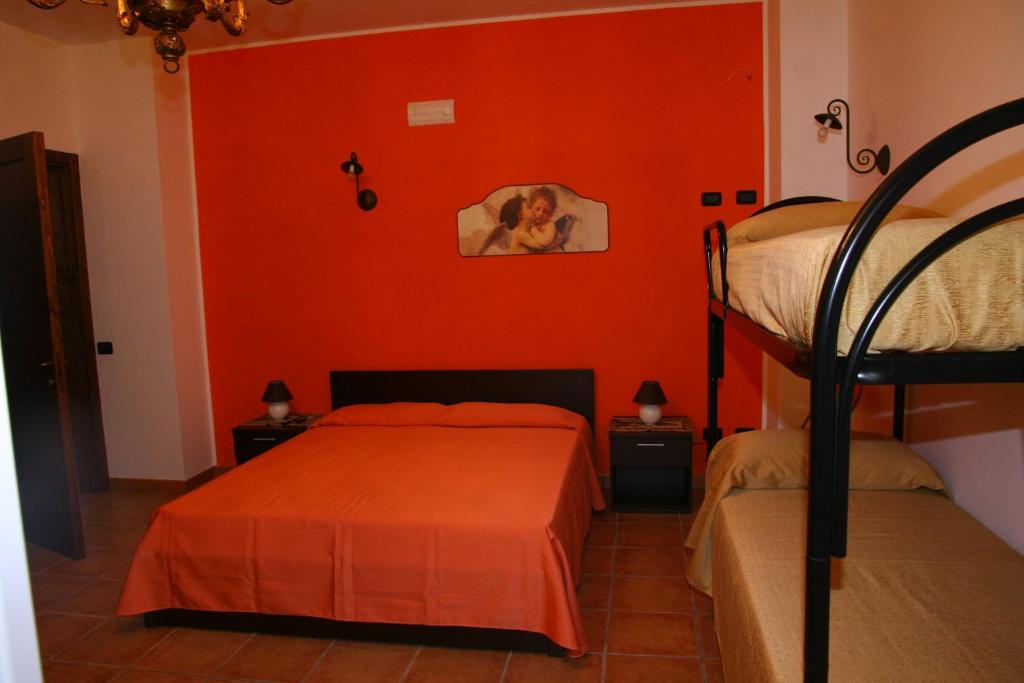 a bedroom with two bunk beds and an orange wall at Aira Te Finu in Acquarica