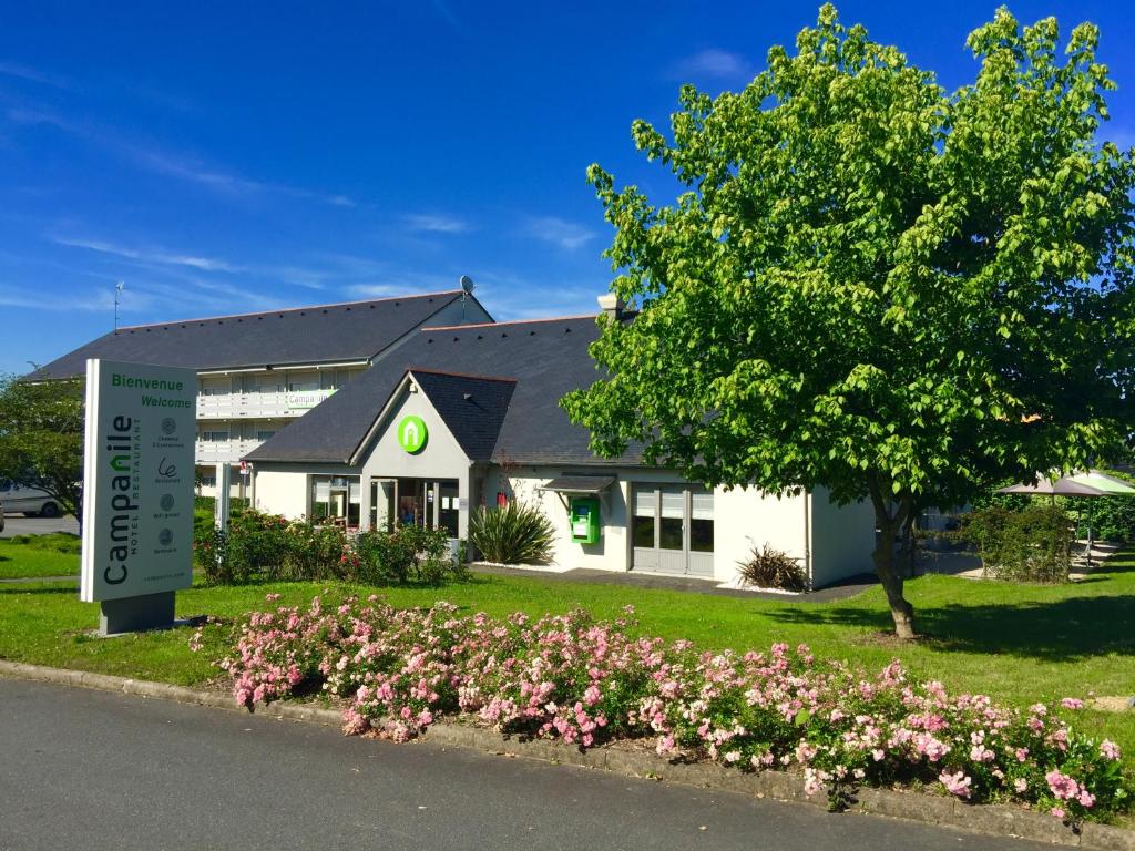 a white building with a tree and pink flowers at Campanile Angers Ouest - Beaucouzé in Beaucouzé