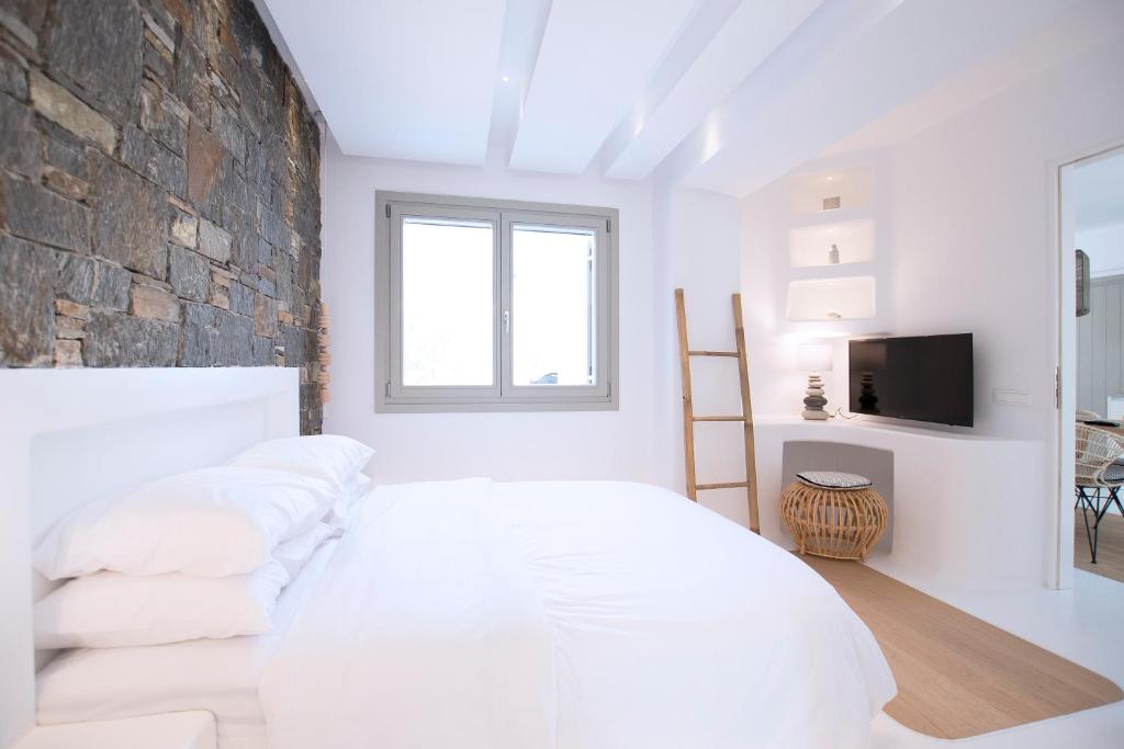 sypialnia z białym łóżkiem i kamienną ścianą w obiekcie Potami Home by Rocks Estates w mieście Nausa