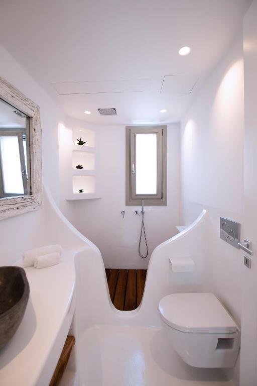 biała łazienka z toaletą i oknem w obiekcie Potami Home by Rocks Estates w mieście Nausa