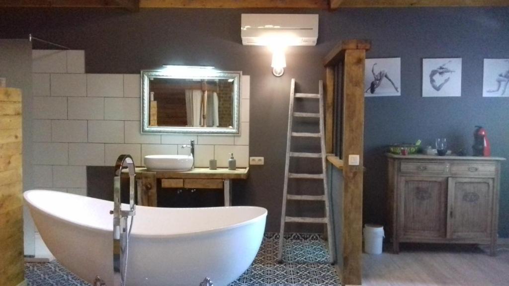 een badkamer met een wit bad en een wastafel bij Les chambres de la Cour in Arsimont