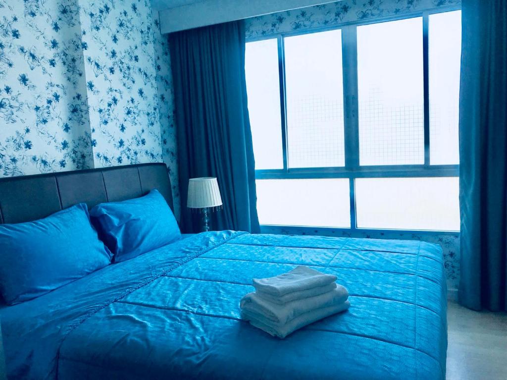 a bedroom with a blue bed with two towels on it at บ้านเพียงเพลิน in Hua Hin