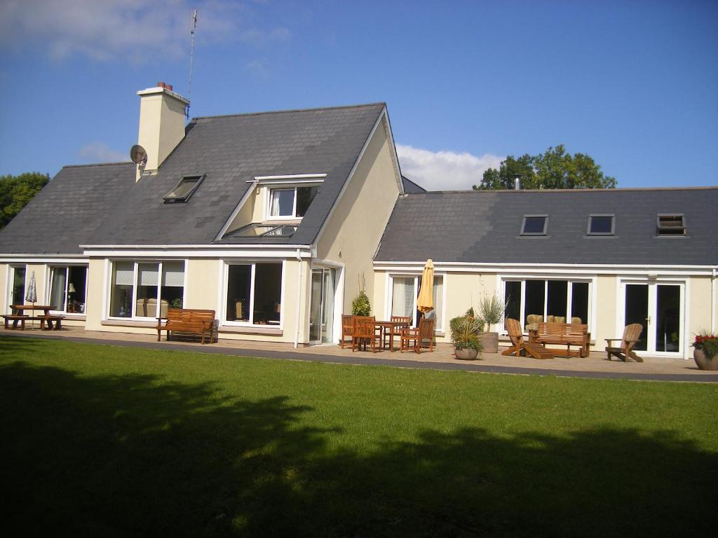 a large white house with benches in front of it at Camillaun Lodge with Lough Corrib Boat Hire in Oughterard