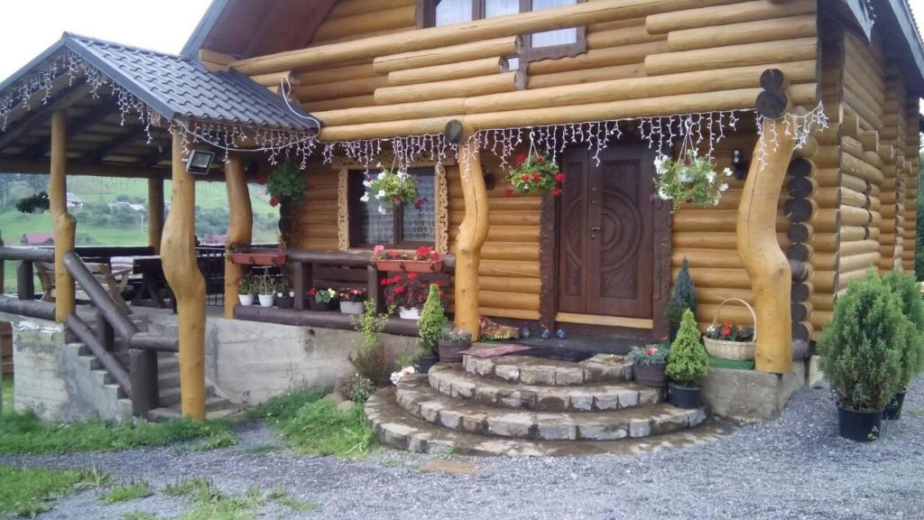 Cette cabane en rondins dispose d'une véranda et d'une porte en bois. dans l'établissement Guest House Dikiy Zrub, à Vorokhta