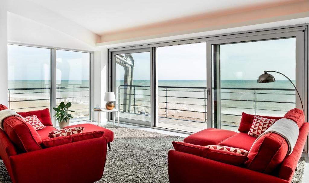 a living room with two red chairs and a view of the ocean at Amazing beach apartment in Lancing