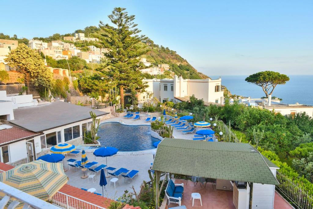 a pool with chairs and umbrellas and the ocean at Hotel Terme Saint Raphael in Ischia