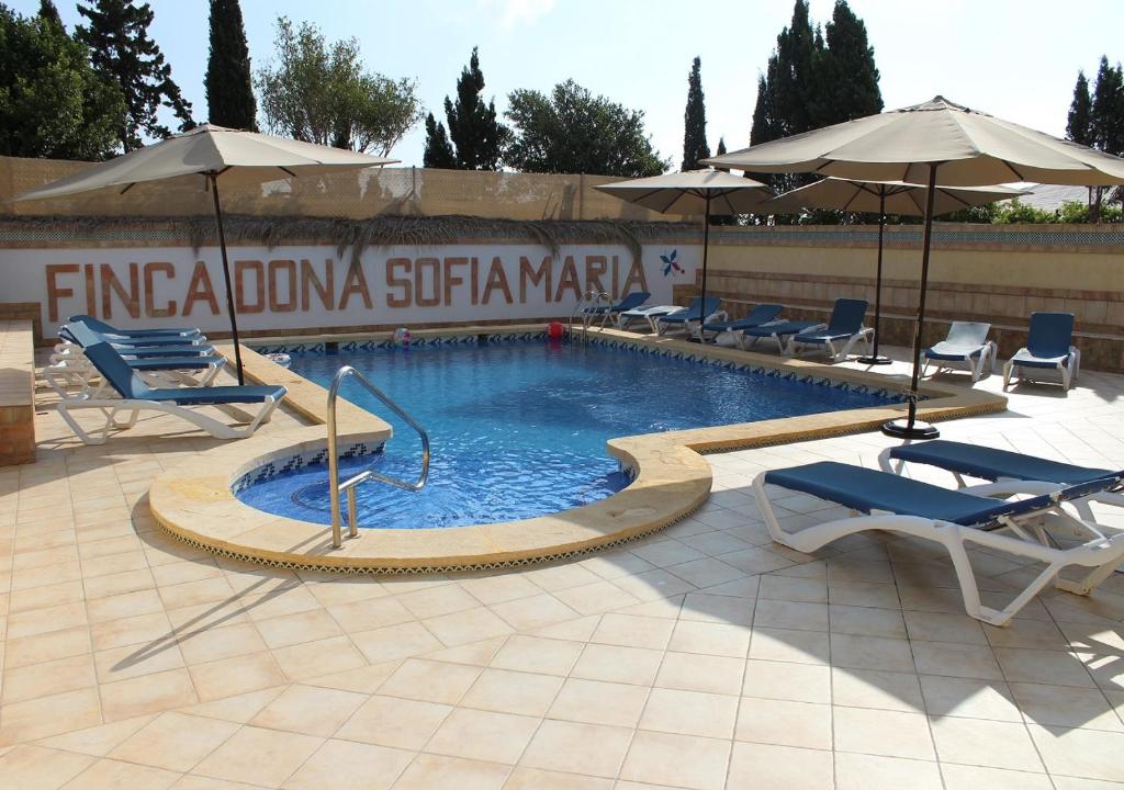 a swimming pool with chairs and umbrellas in a courtyard at Finca Doña Sofia Maria in San Pedro del Pinatar