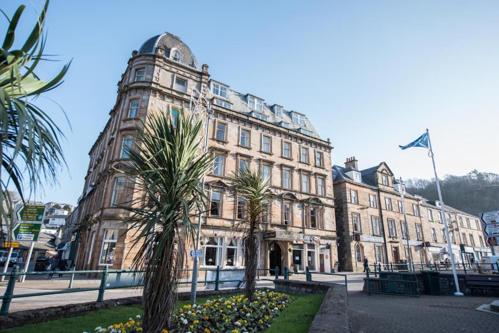 um edifício antigo com palmeiras em frente em The Royal Hotel em Oban