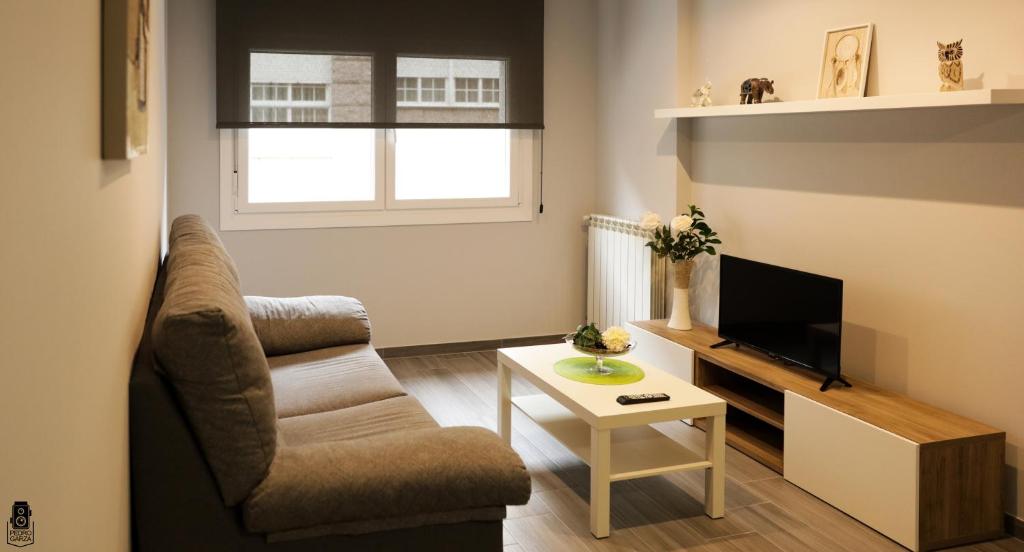 ein Wohnzimmer mit einem Stuhl und einem TV in der Unterkunft dp85 Apartamentos in Sarria