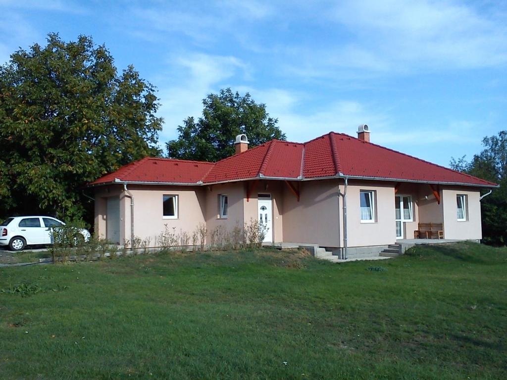 een huis met een rood dak op een grasveld bij Bokros Vendégház in Tordas