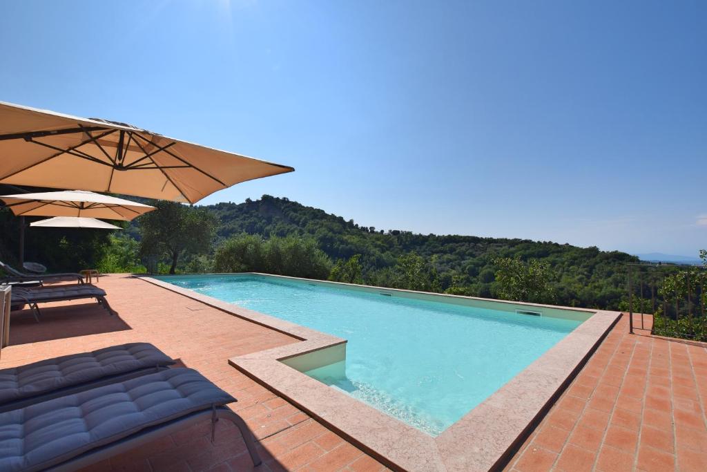 - une grande piscine avec un parasol, des chaises et un parasol dans l'établissement Borgo Gatteraia, à Volterra