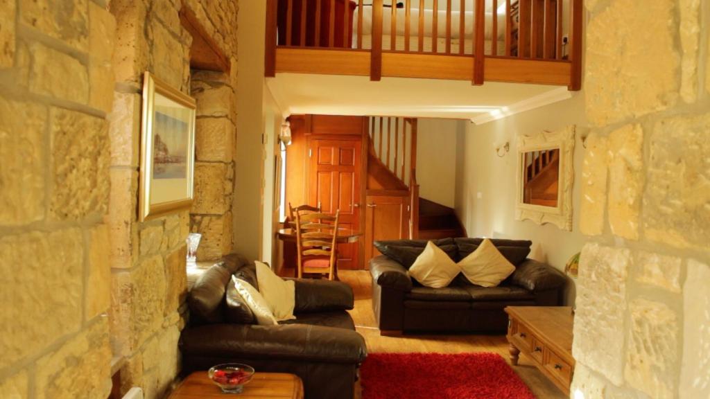 a living room with couches and a stone wall at Smiddy Lodge in Balloch