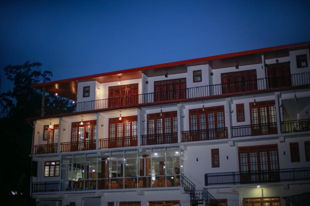 a large white building with red windows at night at Hotel City Grand Ella in Ella