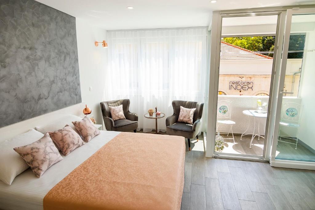 a bedroom with a bed and a balcony with chairs at Rose Gold Rooms & Studio with balcony in Split