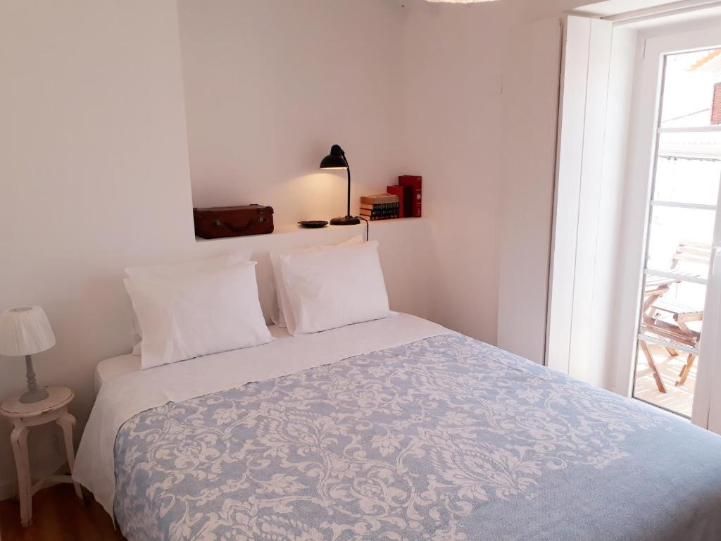 a bedroom with a bed with white sheets and a window at Casa da Sé in Angra do Heroísmo
