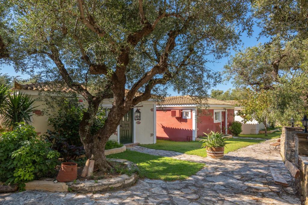 ein Haus mit einem Baum im Hof in der Unterkunft Ilyessa Cottages in Méson Yerakaríon