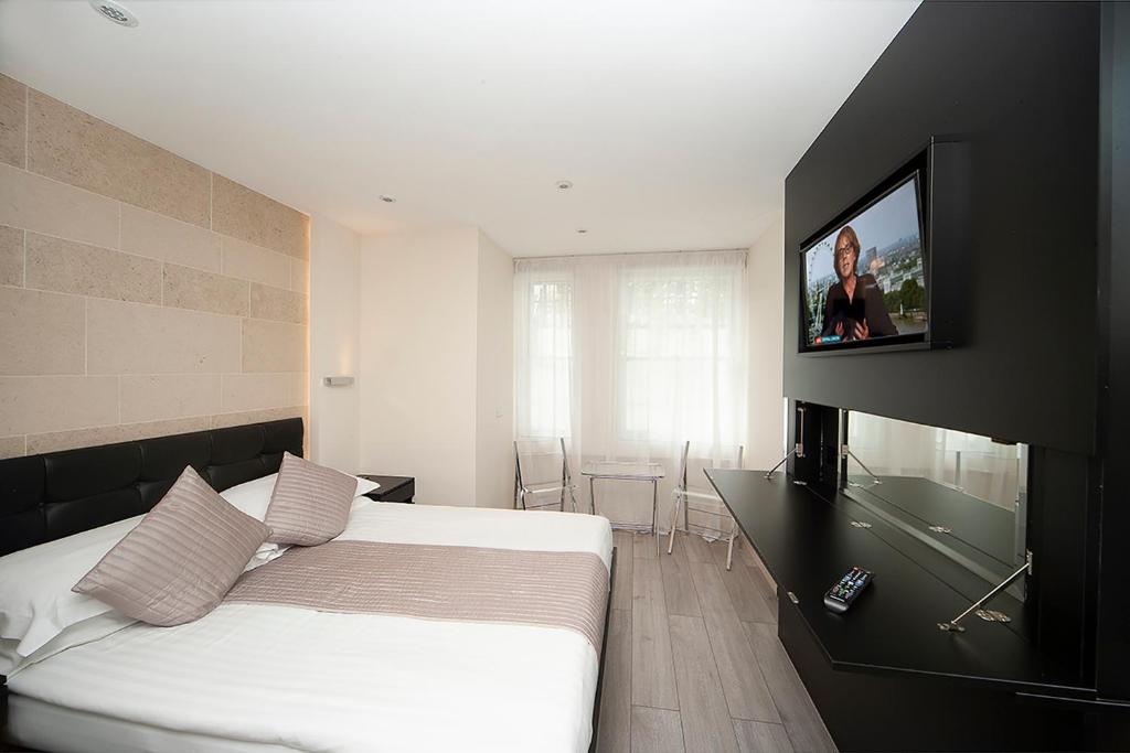sypialnia z łóżkiem i telewizorem z płaskim ekranem w obiekcie NOX Kensington w Londynie