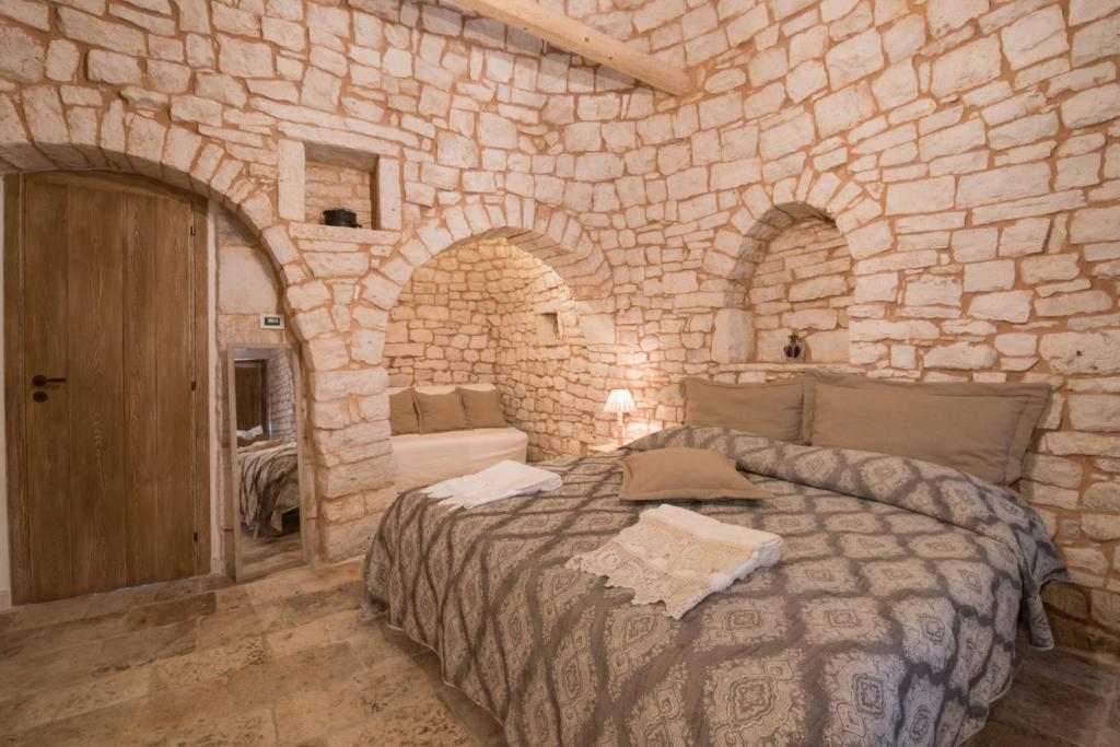 um quarto com uma cama grande numa parede de pedra em Trulli Antichi Mestieri - Widespread Trulli in the historic center em Alberobello