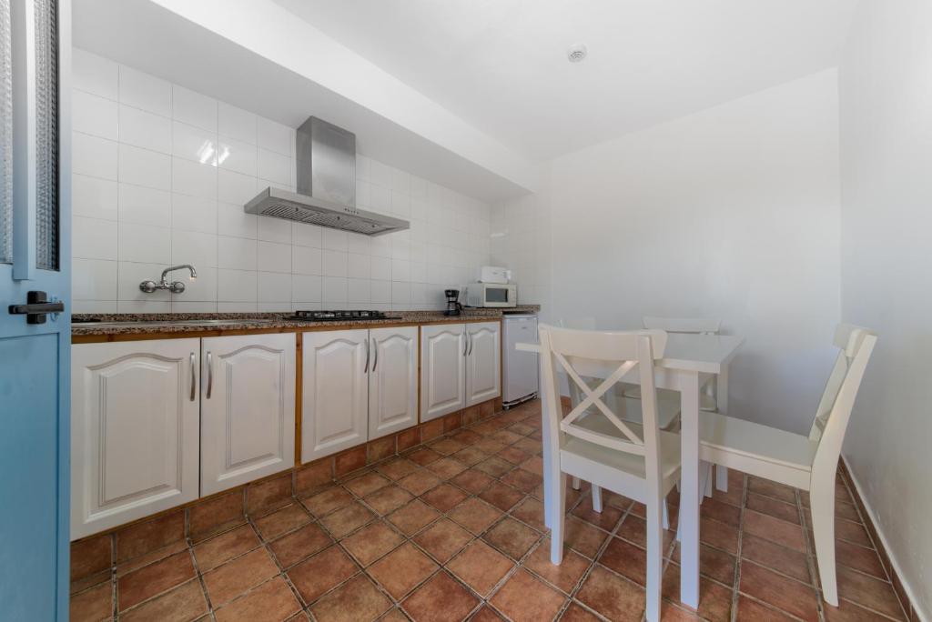 a kitchen with white cabinets and a table and chairs at Dulce Nombre Hotel - Apartamentos in Tarifa