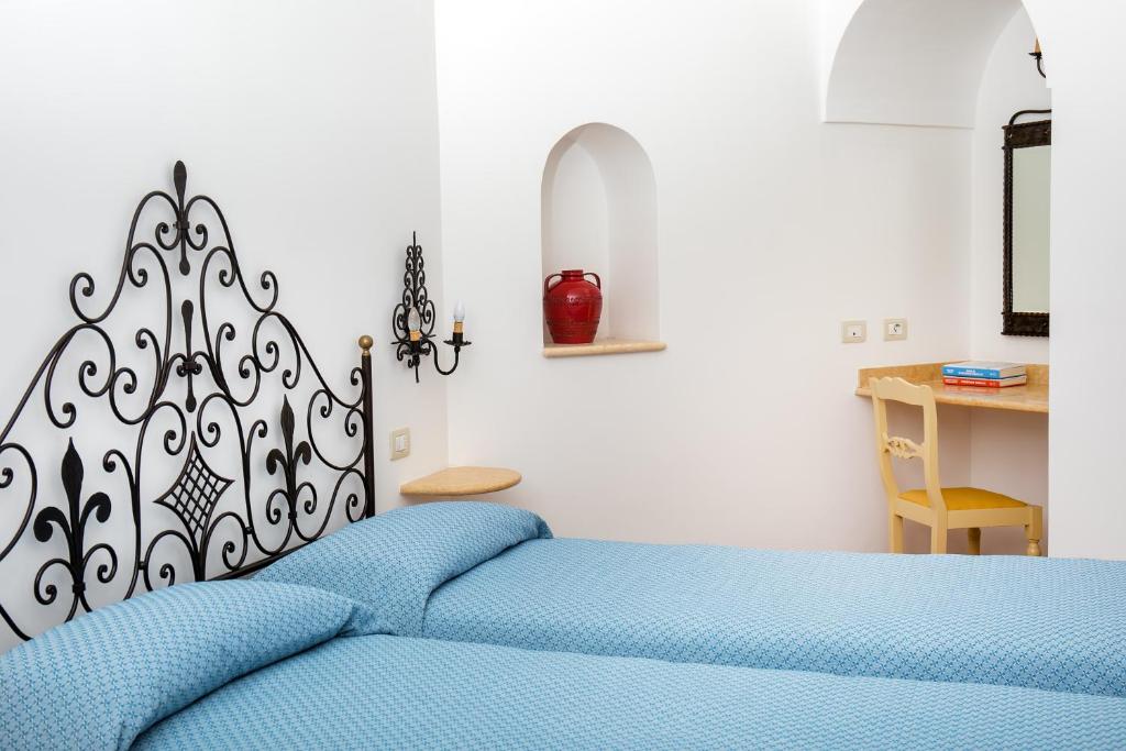 a bedroom with a blue bed with a black and white headboard at Hotel Pupetto in Positano