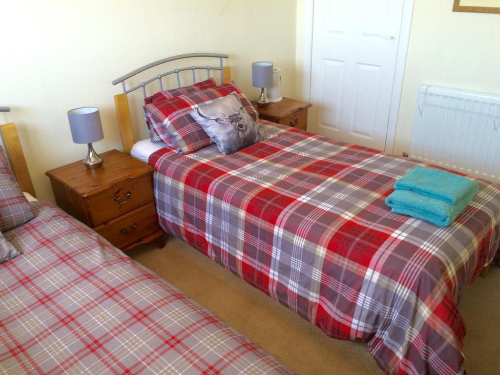 a bedroom with two twin beds and two lamps at Inverkenny House in Inverness