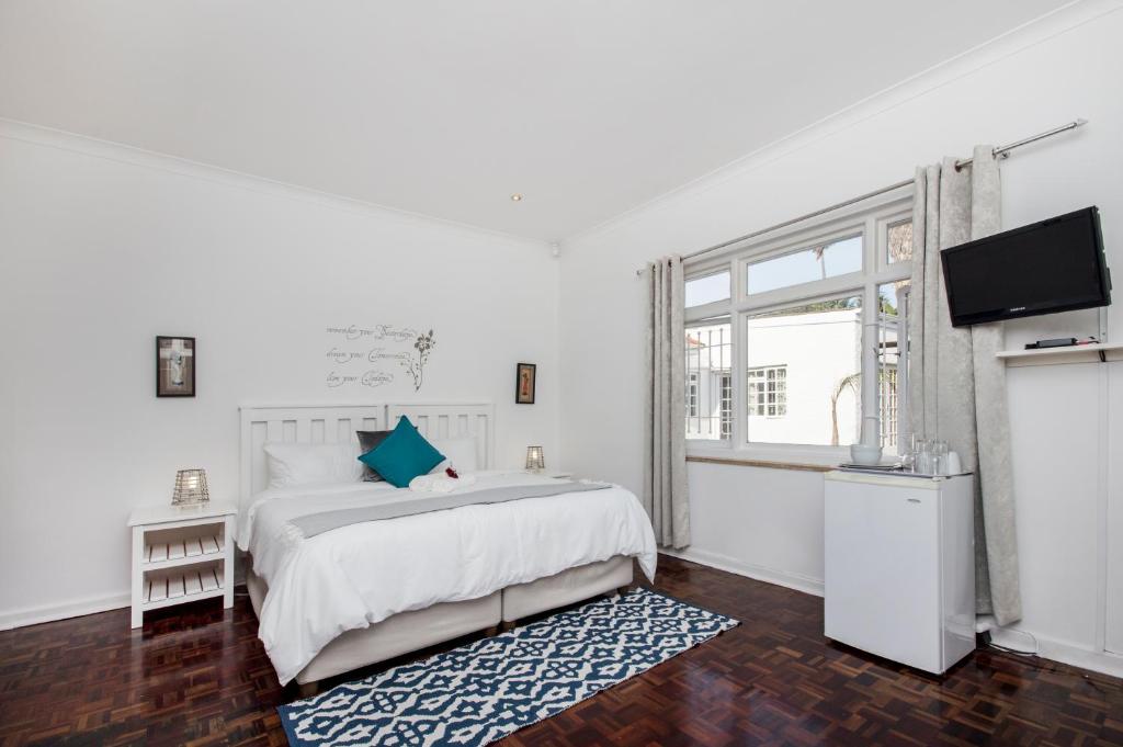 una camera da letto bianca con un letto e una TV di Emabaleni Guest House PTY LTD a Port Elizabeth