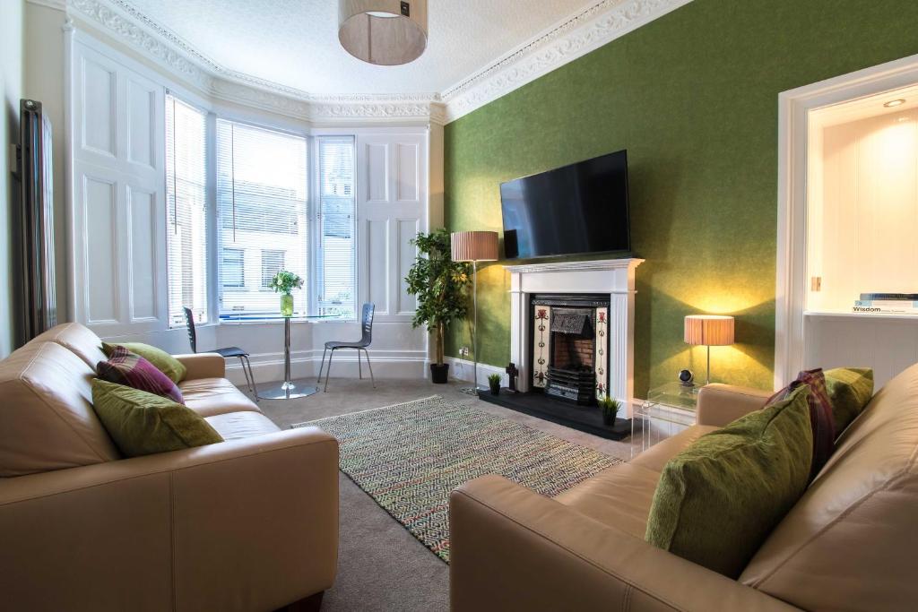 a living room with a couch and a fireplace at West Highland Apartments Milngavie - The Nevis in Milngavie