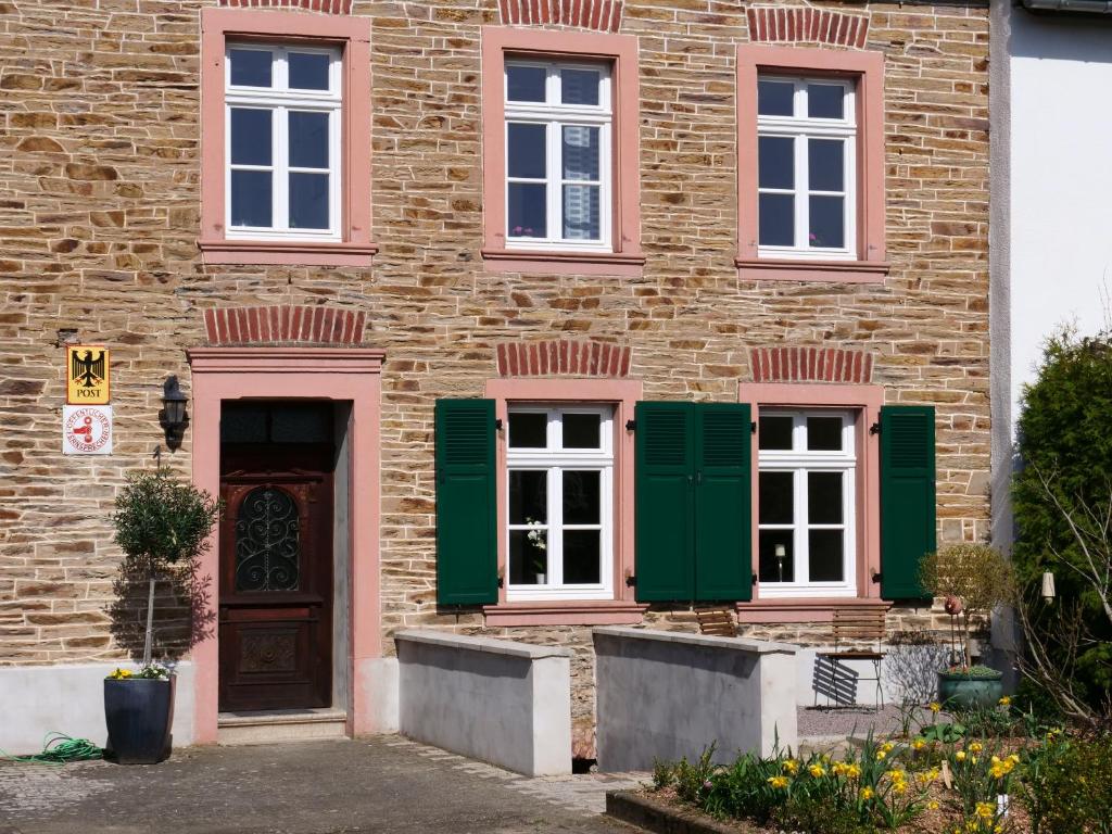 メーリングにあるAltes Lörscher Winzerhausの緑の艶戸と扉のあるレンガ造りの家