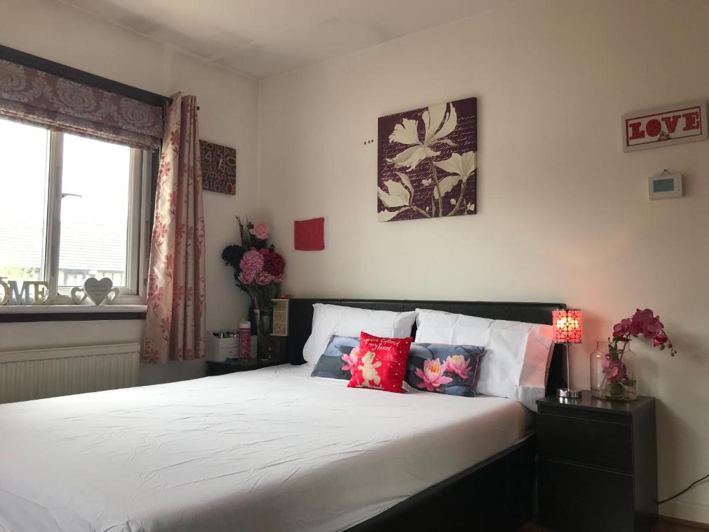 1 dormitorio con 1 cama con sábanas blancas y almohadas rojas en Spacious House 15min to Canary Wharf/O2/Excel/Central London, en Londres