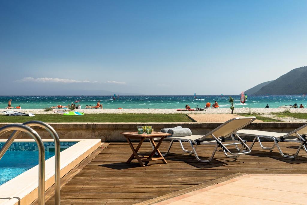 Aktes villas في فاسيليكي: مسبح مع كرسيين وطاولة بجانب شاطئ