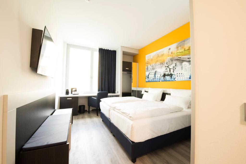 デュッセルドルフにあるカラットホテル デュッセルドルフ シティのベッド2台とデスクが備わるホテルルームです。