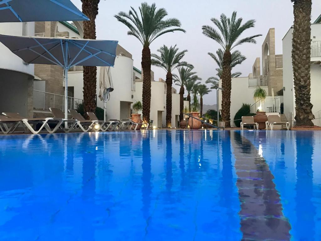 a large swimming pool with palm trees and an umbrella at Lagoon suite in Eilat