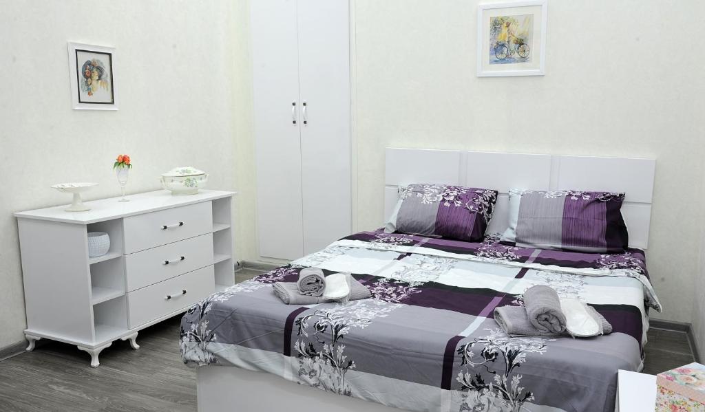 a white bedroom with a bed and a dresser at Sweet Home at Sololaki in Tbilisi City