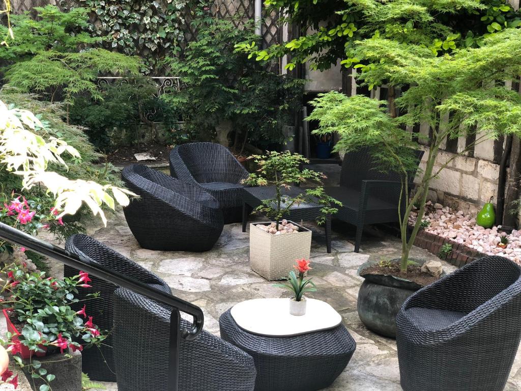 a patio with chairs and a table and plants at Hôtel De La Cathédrale in Rouen