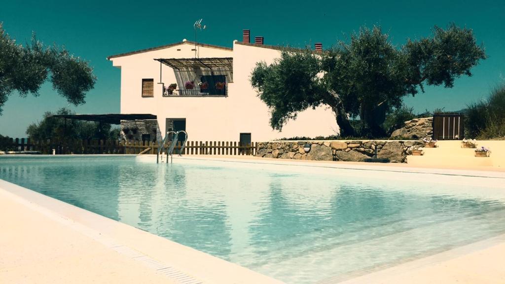 una piscina con una casa en el fondo en Casa Rural Flores Amarillas, en Almoharín