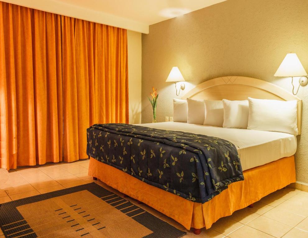 sypialnia z dużym łóżkiem z pomarańczowymi zasłonami w obiekcie Plaza Inn Express w mieście Tapachula