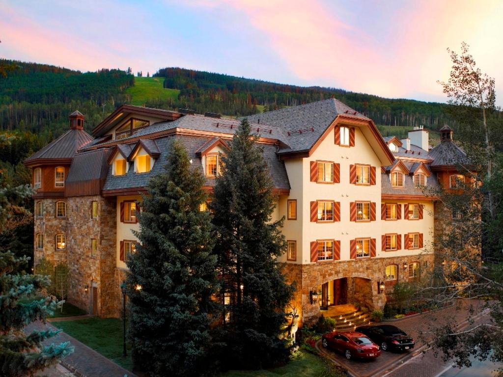 une grande maison avec des voitures garées devant elle dans l'établissement Tivoli Lodge, à Vail